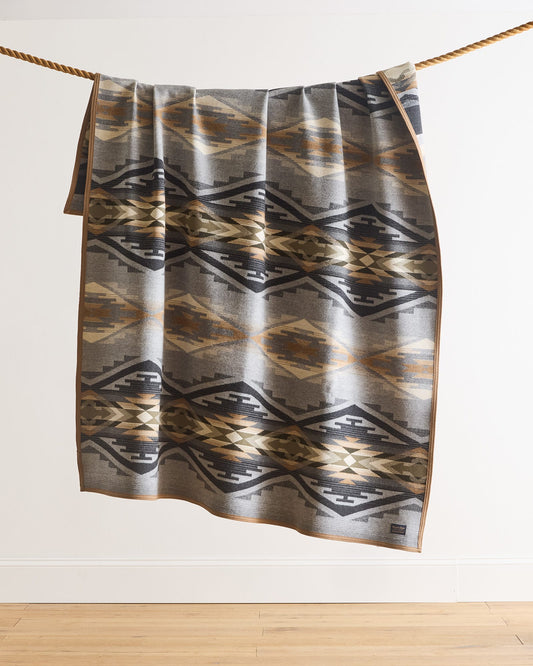 Patterned towel hanging on a rope against a white wall.