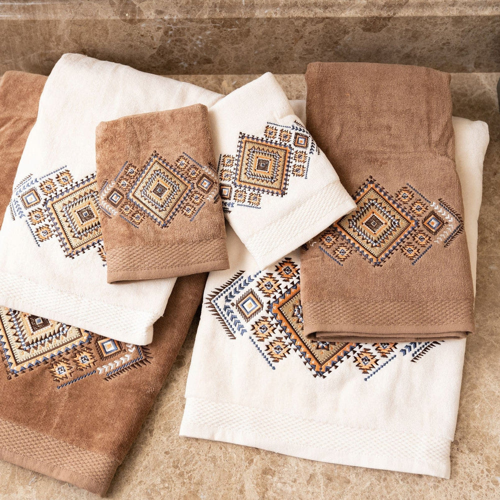 Set of brown and white towels with geometric patterns on a stone surface