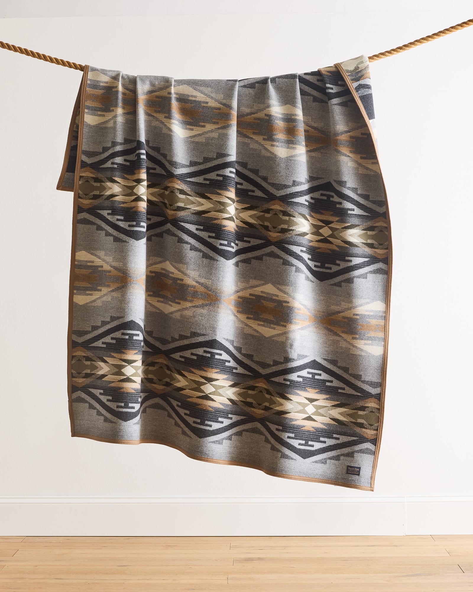 Patterned towel hanging on a rope against a white wall.