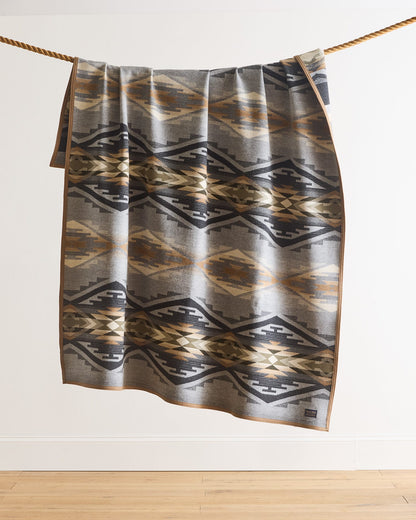 Patterned towel hanging on a rope against a white wall.