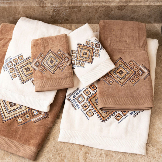 Set of brown and white towels with geometric patterns on a stone surface