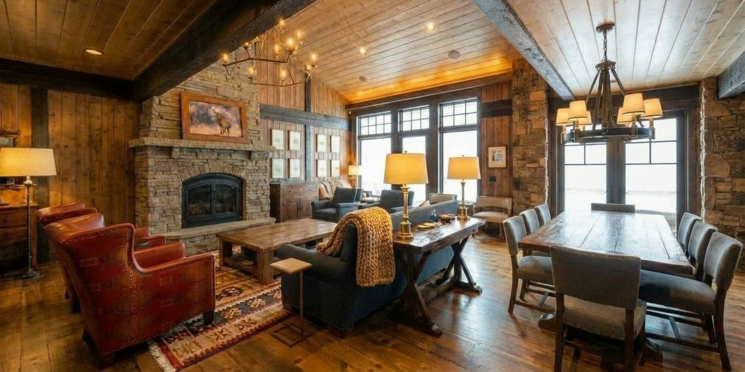 Cozy living room with wooden floors, stone fireplace, and large windows.